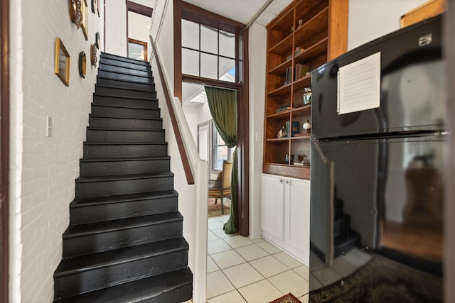 stairway with tile patterned floors and brick wall