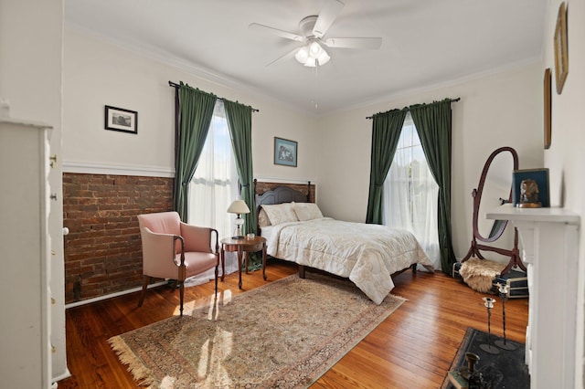 bedroom with multiple windows, ceiling fan, brick wall, and hardwood / wood-style flooring