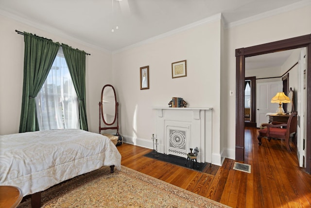 bedroom with ceiling fan, a fireplace, dark hardwood / wood-style flooring, and crown molding