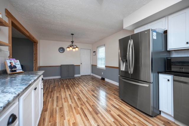 kitchen with tasteful backsplash, appliances with stainless steel finishes, a chandelier, white cabinets, and light wood-type flooring