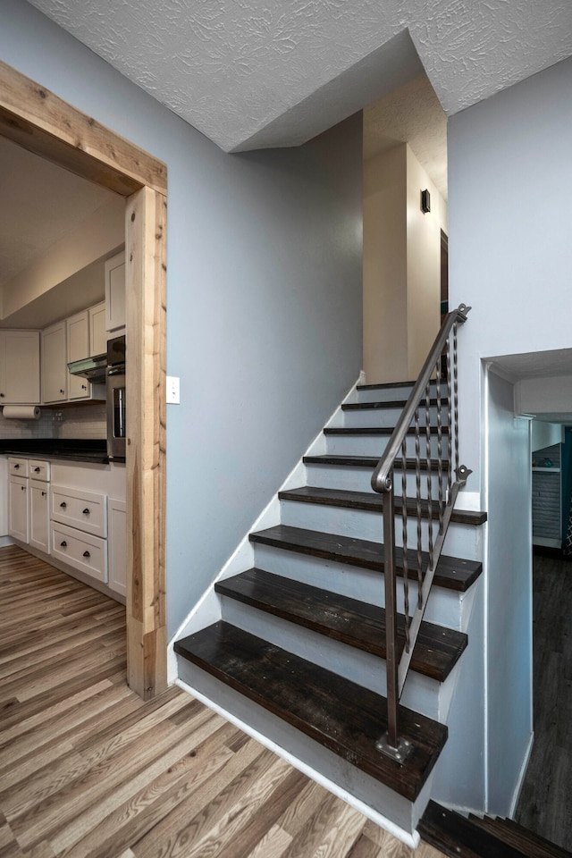 stairway featuring wood-type flooring and a textured ceiling