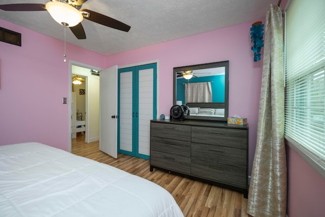 bedroom with a textured ceiling, light hardwood / wood-style flooring, and ceiling fan