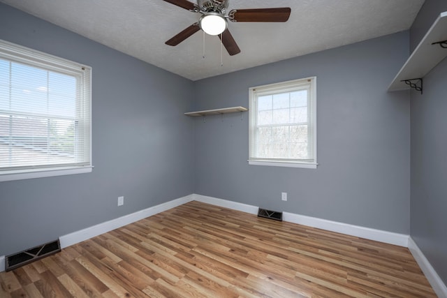 spare room with a textured ceiling, light wood-type flooring, and ceiling fan