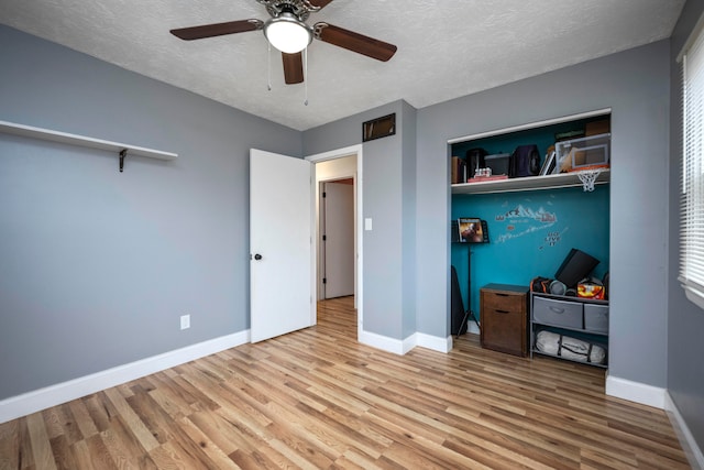 unfurnished bedroom featuring ceiling fan, a closet, a textured ceiling, and hardwood / wood-style flooring