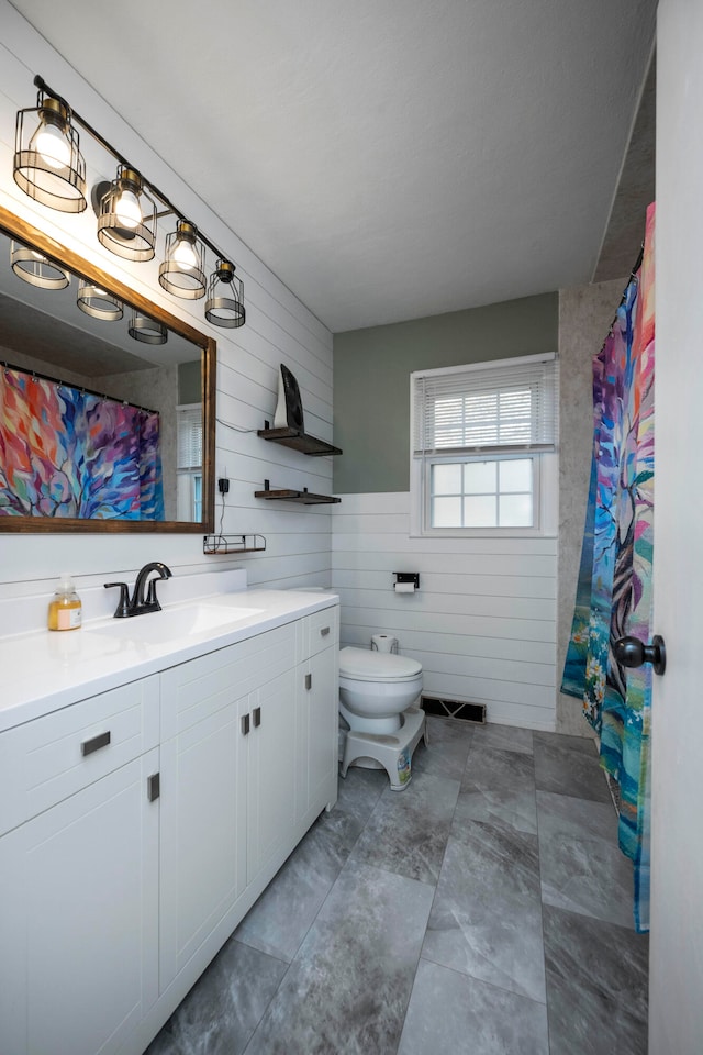 bathroom with wooden walls, vanity, and toilet