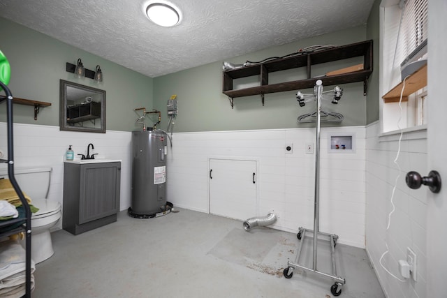 washroom with a textured ceiling, electric water heater, hookup for a washing machine, and electric dryer hookup