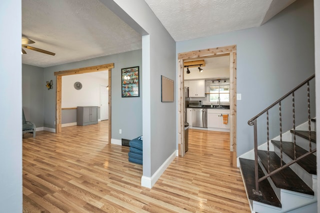 corridor featuring light hardwood / wood-style flooring, a textured ceiling, and sink