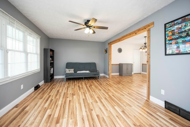 unfurnished room with ceiling fan with notable chandelier, a textured ceiling, and light wood-type flooring