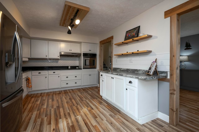 kitchen featuring white cabinets, light hardwood / wood-style floors, stainless steel appliances, and a textured ceiling