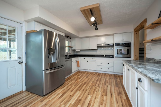 kitchen with decorative backsplash, light wood-type flooring, stainless steel appliances, sink, and white cabinetry