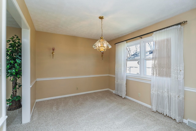 carpeted spare room with a chandelier