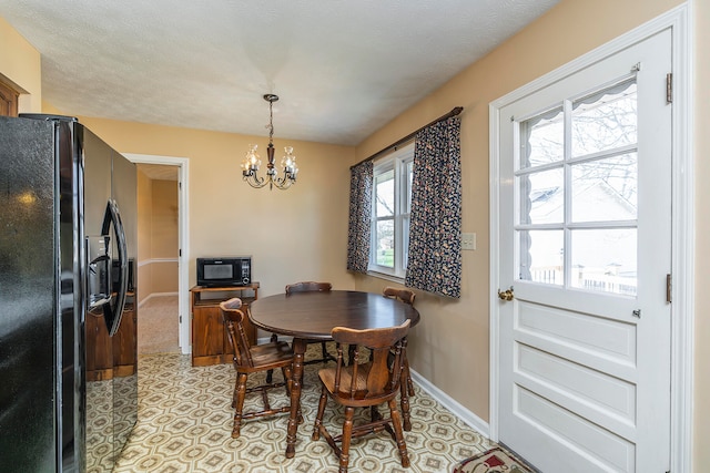 dining area featuring a wealth of natural light, a textured ceiling, and an inviting chandelier