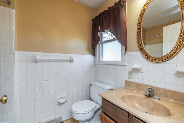 bathroom with a textured ceiling, vanity, toilet, and tile walls