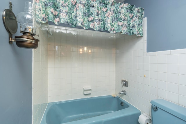 bathroom with toilet, tile walls, and tiled shower / bath