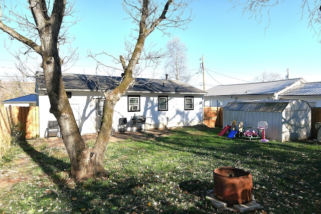 rear view of house with a lawn and a storage unit