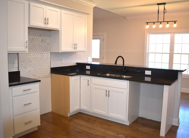 kitchen with white cabinets, backsplash, dark wood-style flooring, a sink, and a peninsula