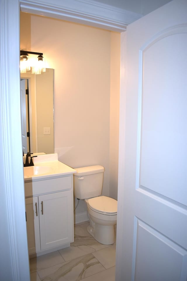 bathroom with toilet, marble finish floor, and vanity