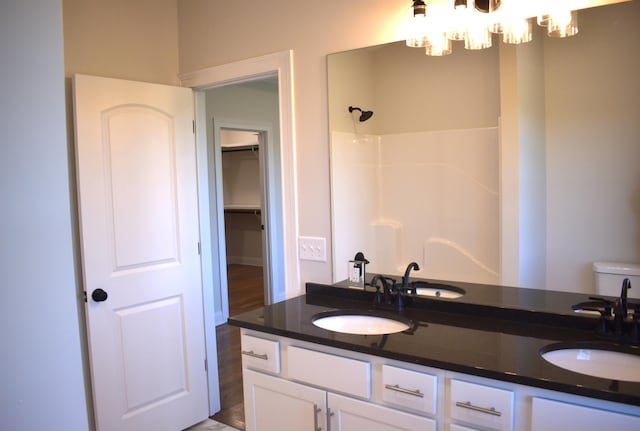 bathroom featuring an inviting chandelier, walk in shower, and a sink