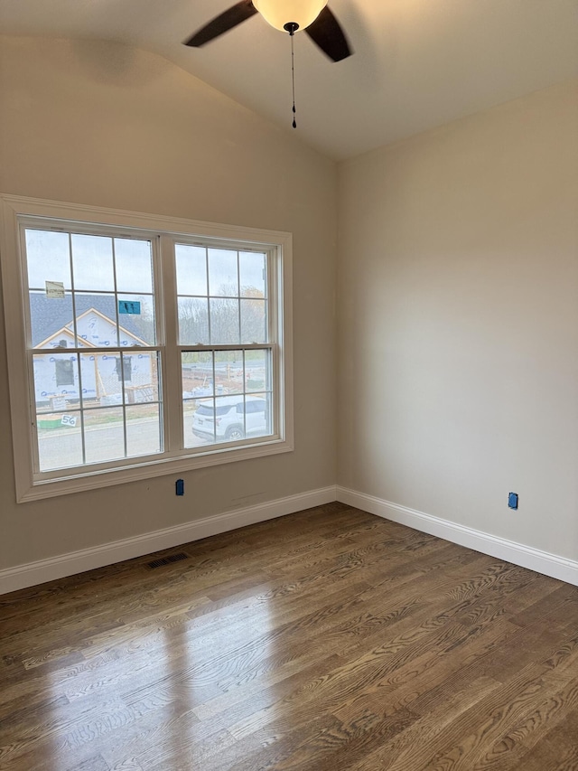 empty room with dark wood finished floors, baseboards, ceiling fan, and vaulted ceiling