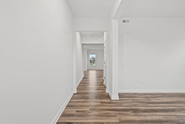 corridor featuring dark wood-style floors, visible vents, and baseboards