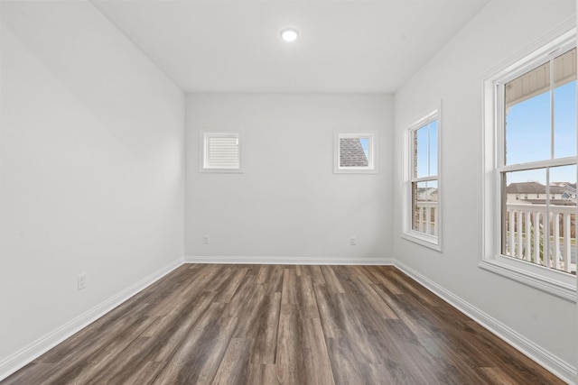 spare room featuring dark wood-type flooring and baseboards