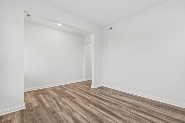 empty room with visible vents, baseboards, and wood finished floors