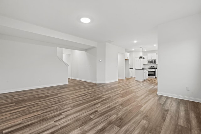 unfurnished living room with recessed lighting, wood finished floors, and baseboards