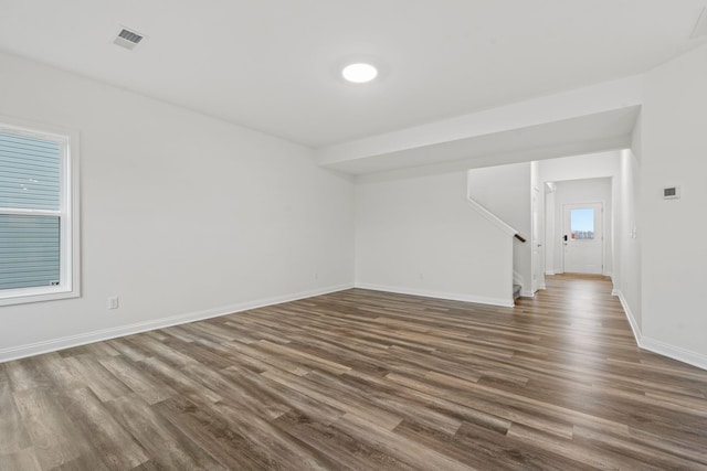 unfurnished room featuring dark wood-type flooring, stairway, visible vents, and baseboards