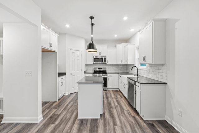 kitchen with stainless steel appliances, a kitchen island, a sink, dark countertops, and dark wood finished floors