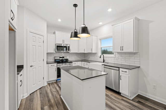 kitchen with a sink, white cabinets, appliances with stainless steel finishes, dark wood-style floors, and dark countertops