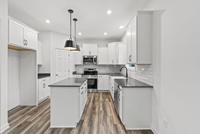 kitchen with dark countertops, appliances with stainless steel finishes, a sink, and a center island