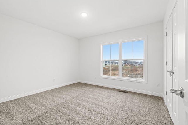 unfurnished room featuring carpet floors, visible vents, and baseboards