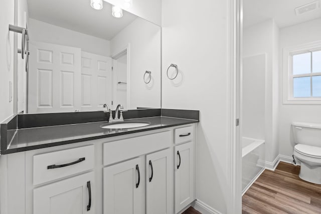 full bath featuring visible vents, toilet, vanity, wood finished floors, and baseboards