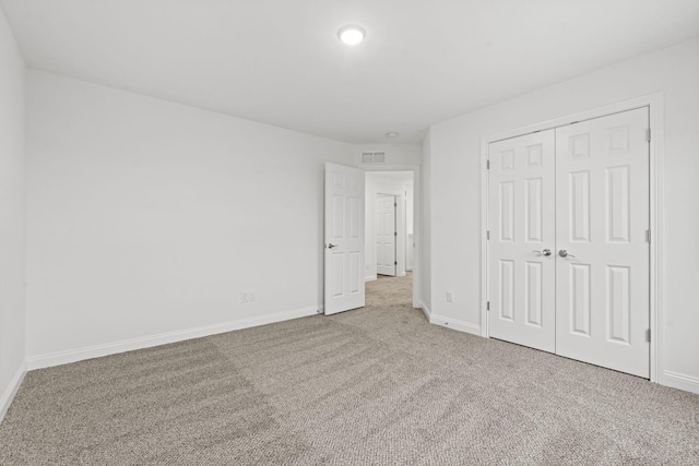 unfurnished bedroom featuring carpet floors, baseboards, visible vents, and a closet