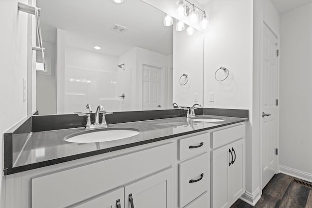 full bath with a shower, visible vents, a sink, and wood finished floors