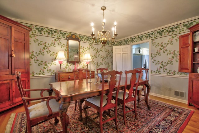 dining area featuring light wood-type flooring, crown molding, and a chandelier