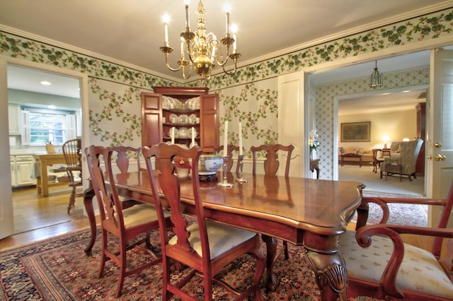 dining space featuring wood-type flooring, an inviting chandelier, and ornamental molding