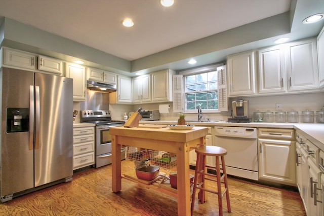 kitchen with light hardwood / wood-style floors, white cabinetry, sink, and appliances with stainless steel finishes