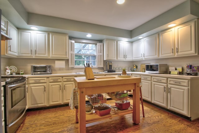 kitchen featuring white cabinets, sink, light hardwood / wood-style floors, and stainless steel electric range