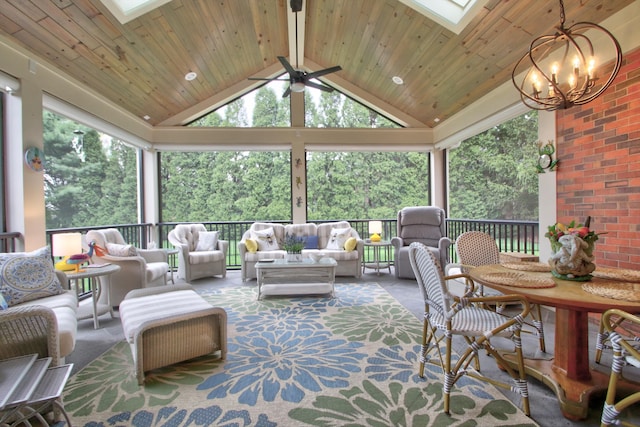 sunroom / solarium with ceiling fan with notable chandelier, vaulted ceiling with skylight, plenty of natural light, and wood ceiling