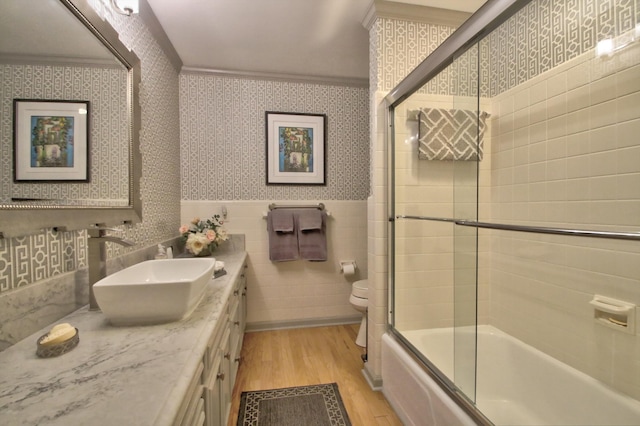 full bathroom with bath / shower combo with glass door, wood-type flooring, toilet, vanity, and ornamental molding