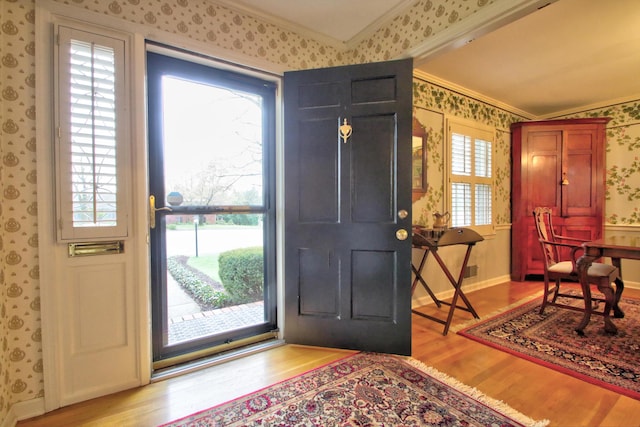 entryway with a healthy amount of sunlight, light hardwood / wood-style floors, and ornamental molding