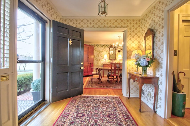 entryway featuring light hardwood / wood-style flooring, a chandelier, and ornamental molding