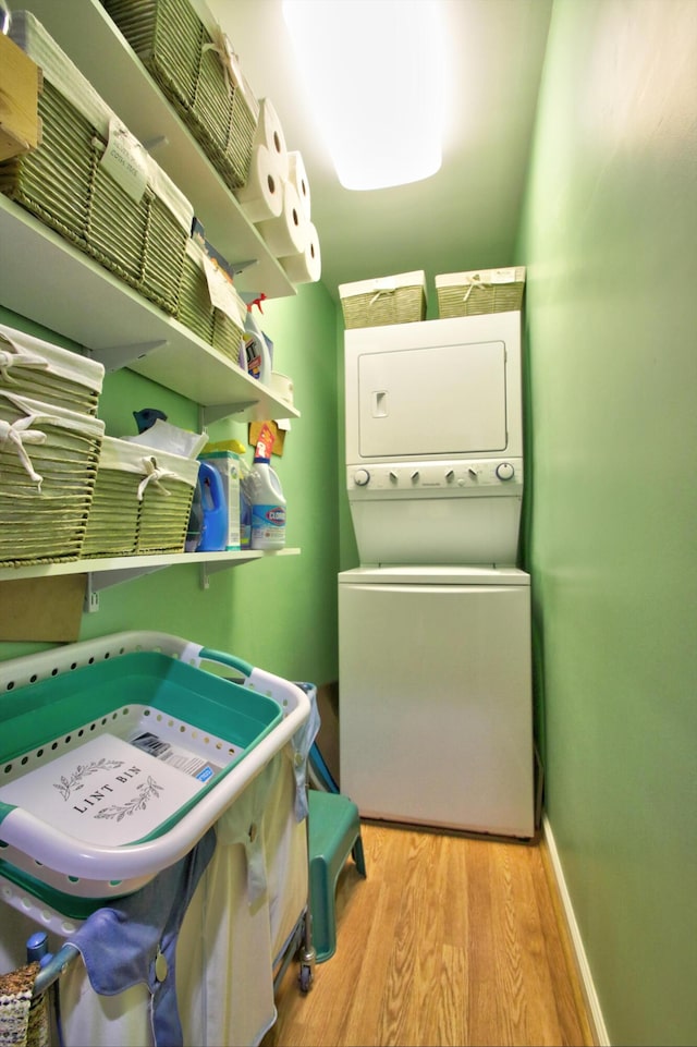 washroom with light wood-type flooring and stacked washer and clothes dryer