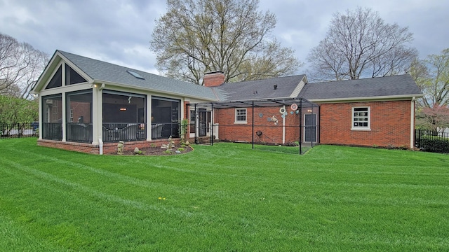 rear view of property featuring a yard and a sunroom