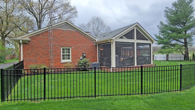 rear view of property with a sunroom, cooling unit, and a lawn