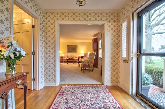 entryway with light hardwood / wood-style floors and crown molding