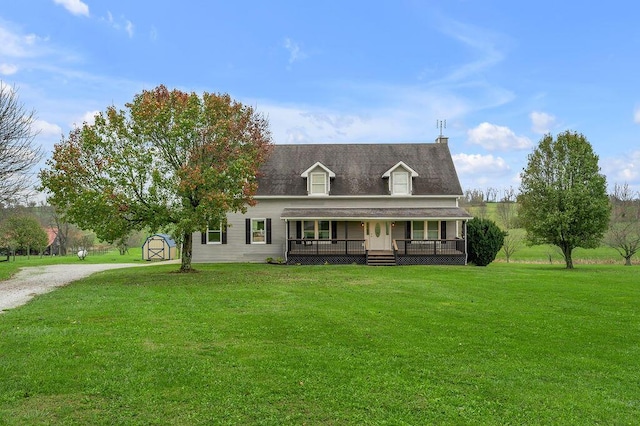 view of front facade with covered porch, a front lawn, and a storage shed