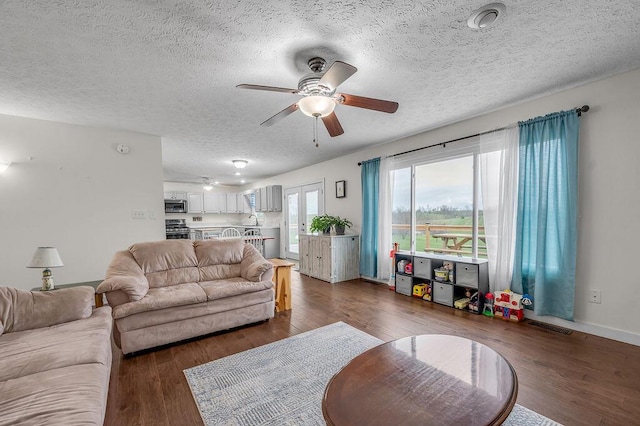 living room with a textured ceiling, ceiling fan, and dark hardwood / wood-style floors