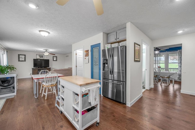 kitchen with stainless steel fridge, a textured ceiling, dark wood-type flooring, and gray cabinetry